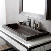 Rectangular slate-colored trough sink with single faucet and accessory holders, mounted on white marble countertop beneath mi