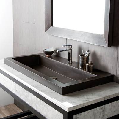 Rectangular slate-colored trough sink with single faucet and accessory holders, mounted on white marble countertop beneath mi