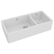 White fireclay apron front kitchen sink with 1.5 bowls and divider, shown from above angle.