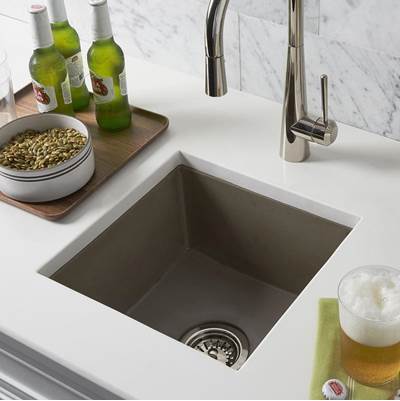 Earth-toned square prep sink with stainless steel faucet, wooden prep board, and beverage bottles on white countertop.