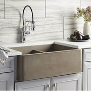 Earth-toned farmhouse double bowl sink with chrome pull-down faucet installed in white kitchen cabinetry.