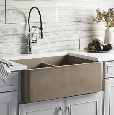 Earth-toned farmhouse double bowl sink with chrome pull-down faucet installed in white kitchen cabinetry.