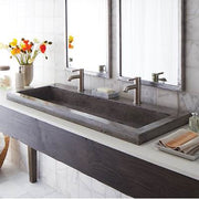 Rectangular ash-colored trough bathroom sink with dual chrome faucets mounted on marble countertop.