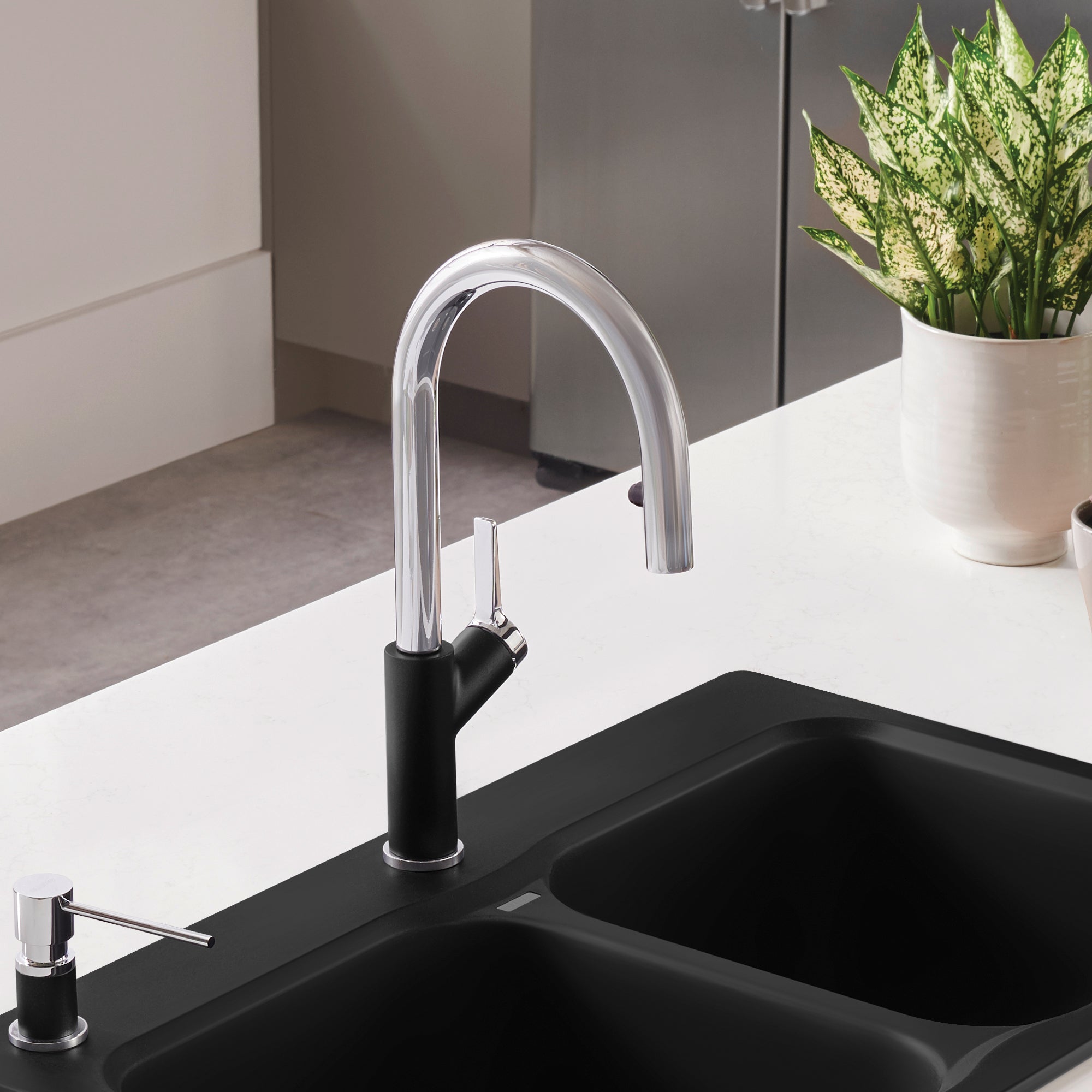Chrome and coal black pull-down kitchen faucet with curved spout mounted above black double sink.