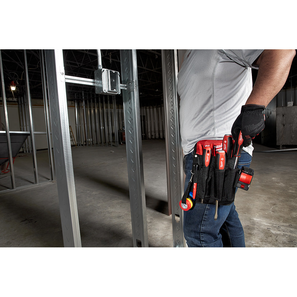 Ten Milwaukee screwdrivers with red handles stored in a black tool belt worn by a worker.