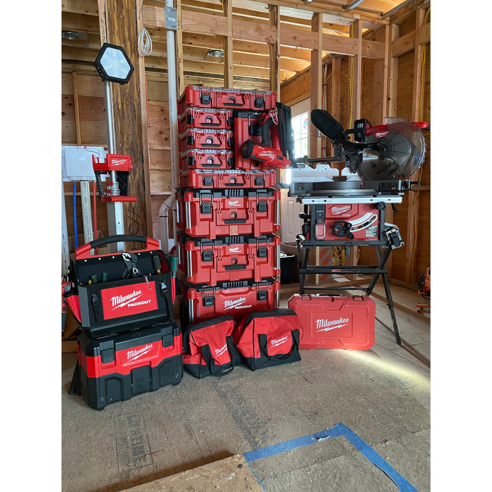 Red and black Milwaukee PACKOUT compact organizer with multiple stacked compartments displayed in workshop setting.