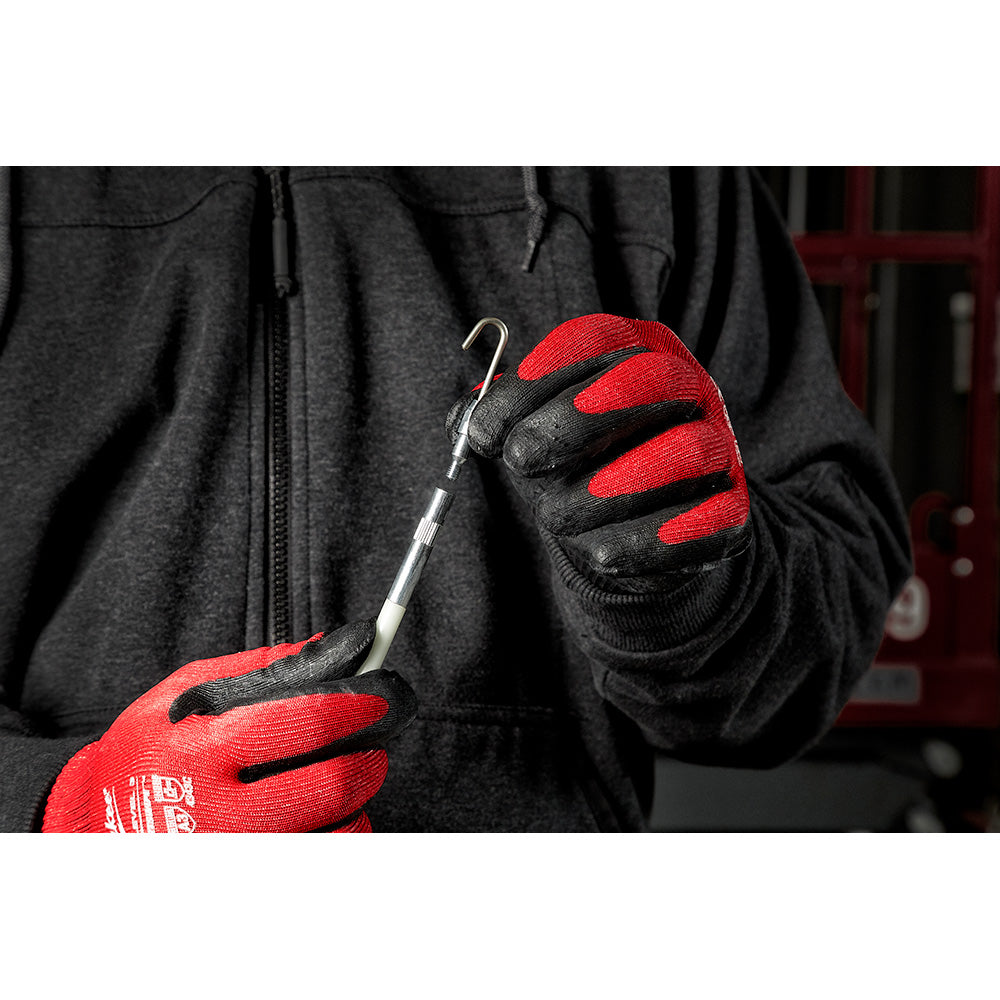 Person in red and black work gloves holding three metal fish stick accessories with hooks and curved ends.