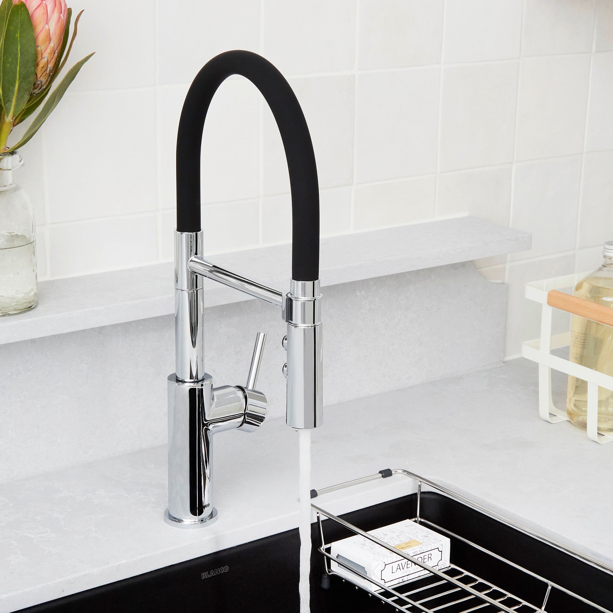 Chrome kitchen faucet with black flexible hose and single lever handle mounted above sink.