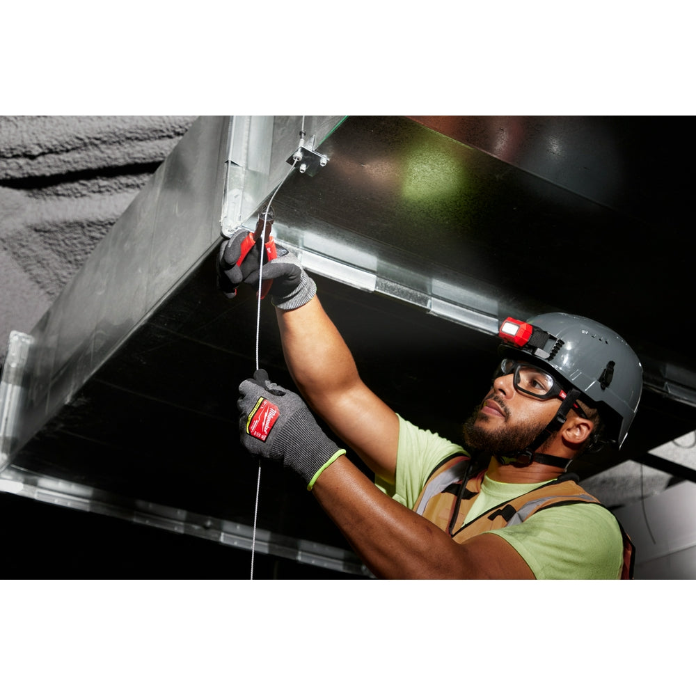 Worker wearing black and red nitrile-dipped gloves while handling electrical equipment overhead.