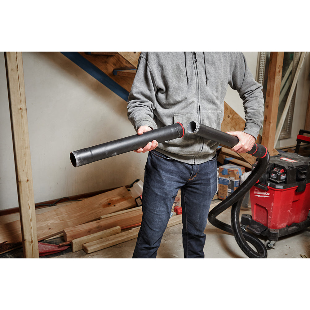 Black cylindrical extension wand with red accents held horizontally by a person in a workshop setting.