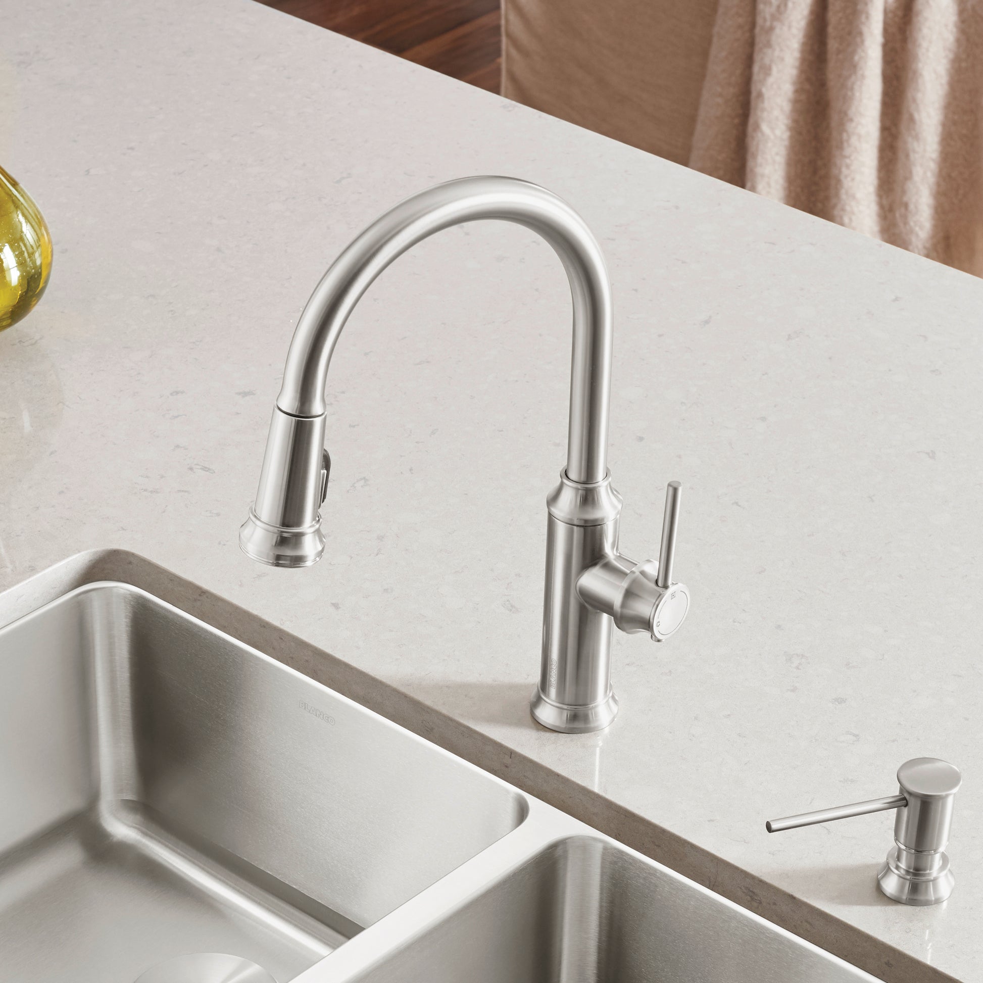 Stainless steel pull-down kitchen faucet with curved spout and single lever handle mounted above double basin sink.