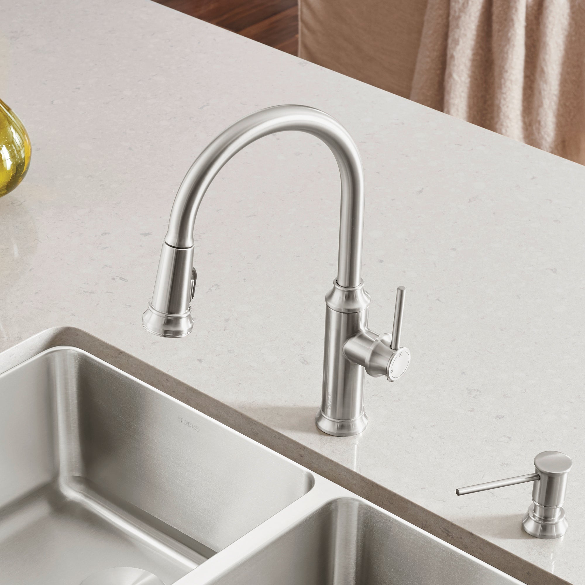 Stainless steel pull-down kitchen faucet with curved spout and single lever handle mounted above double basin sink.