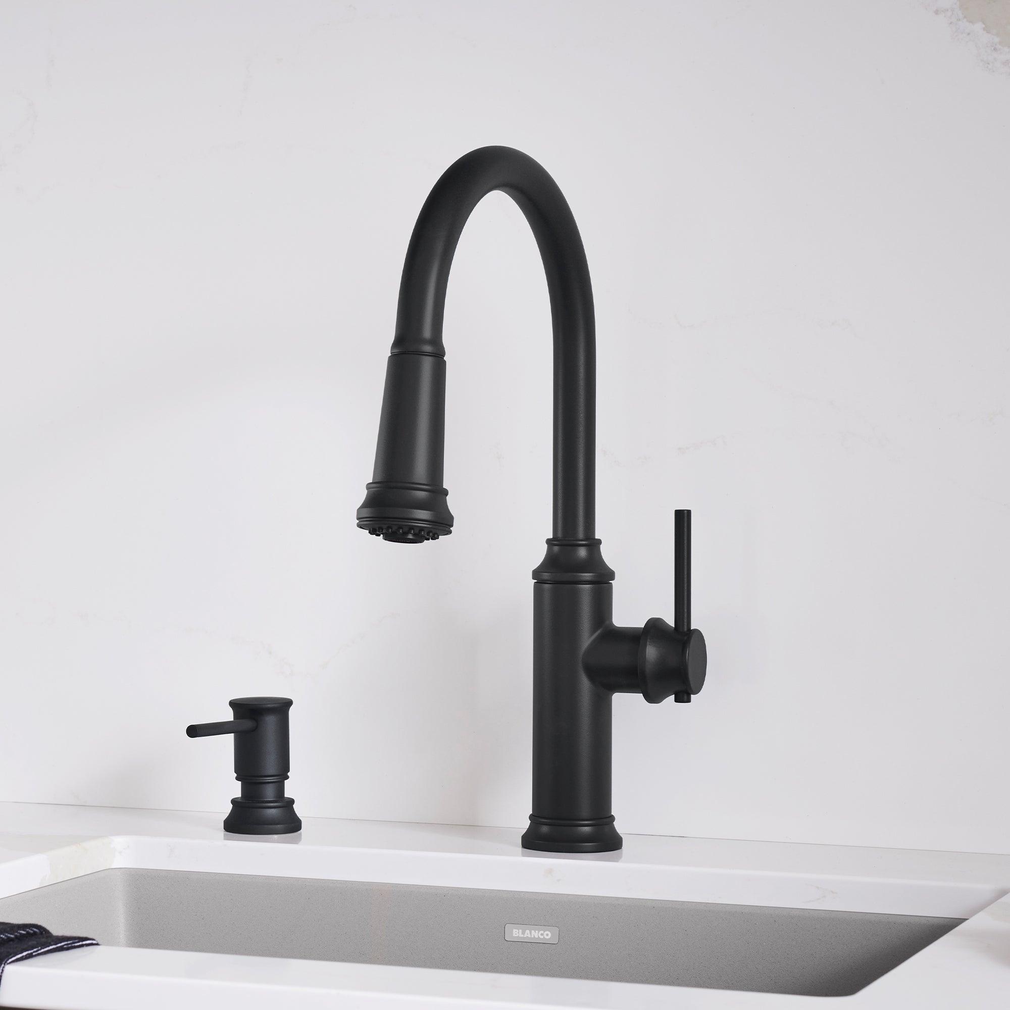 Matte black pull-down kitchen faucet with curved spout and single handle lever, installed over white sink.