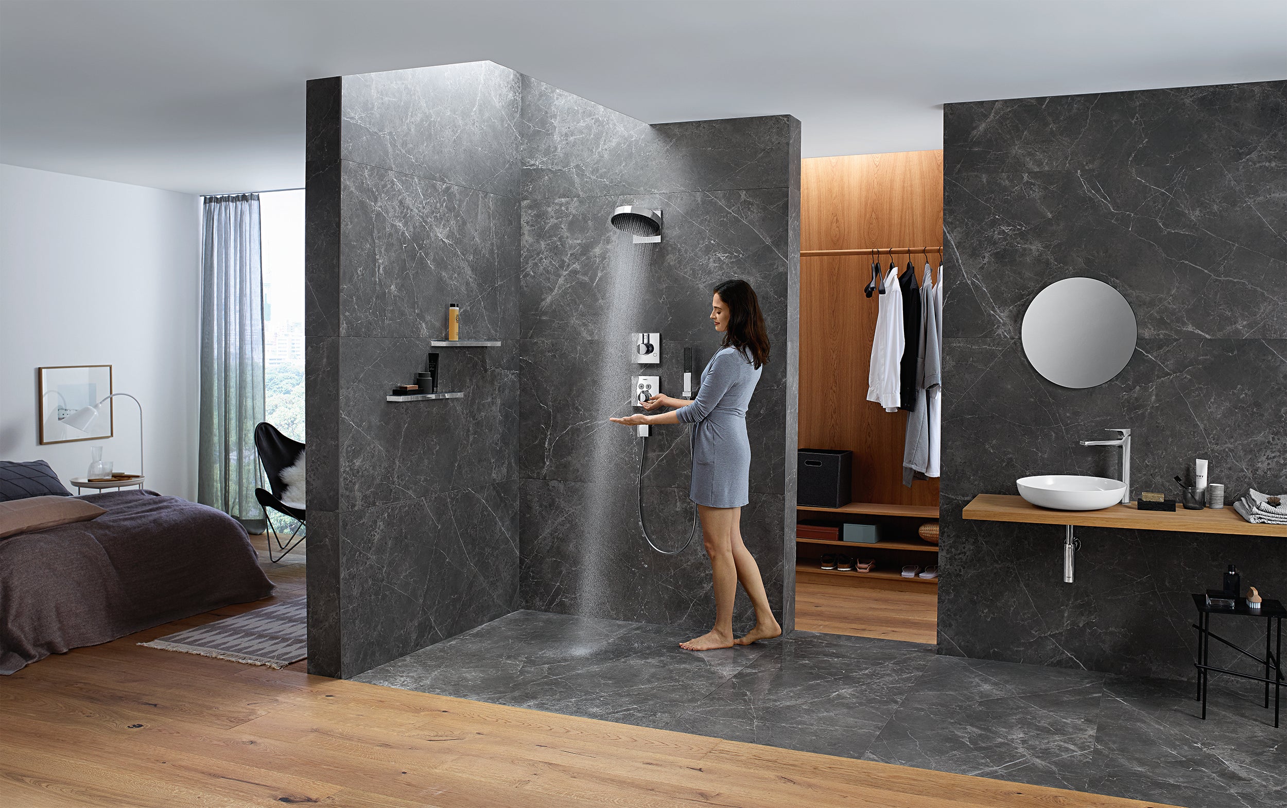 Chrome rainfall showerhead mounted on dark marble shower wall with water streaming downward.