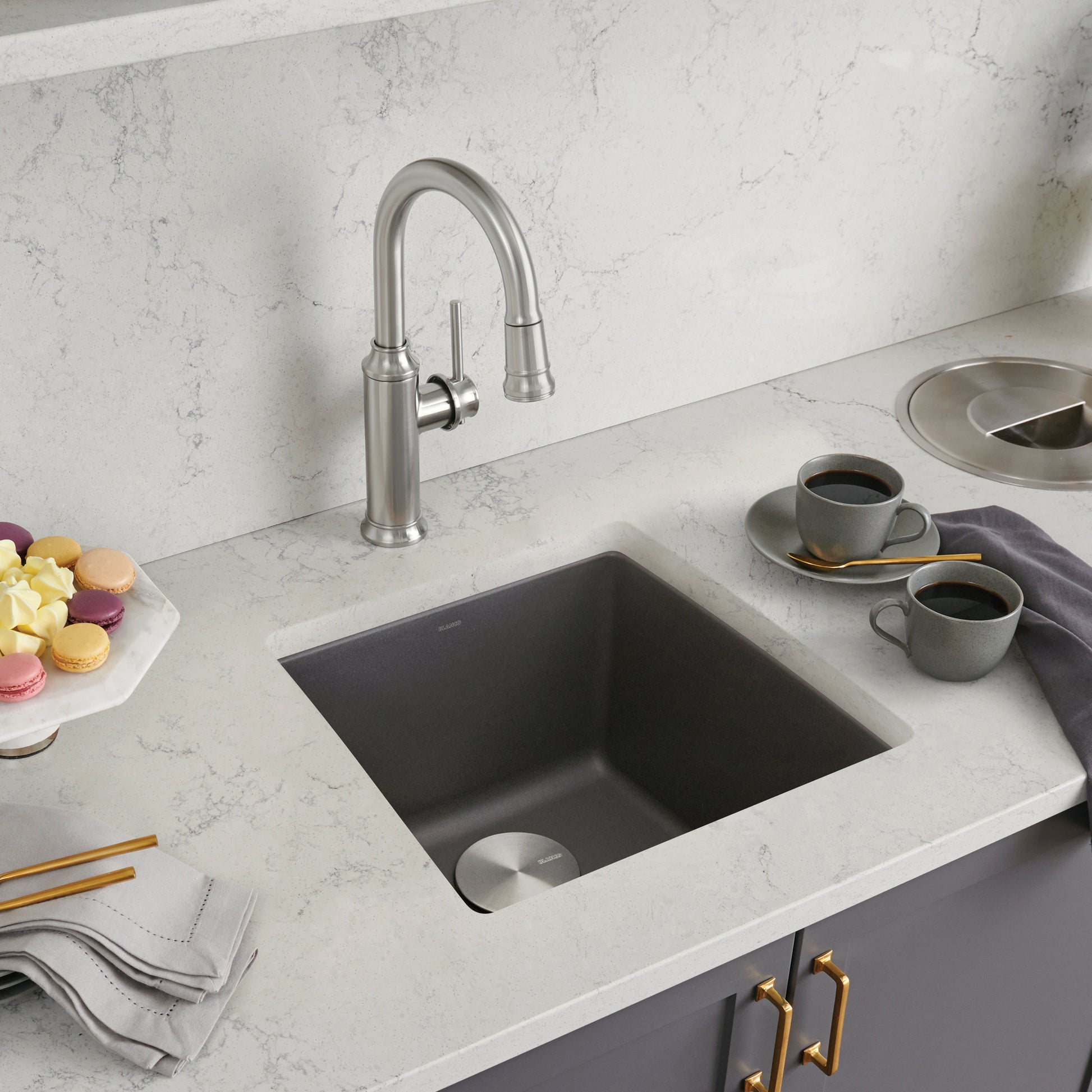 Dark gray square undermount sink with stainless steel faucet installed in white marble countertop.
