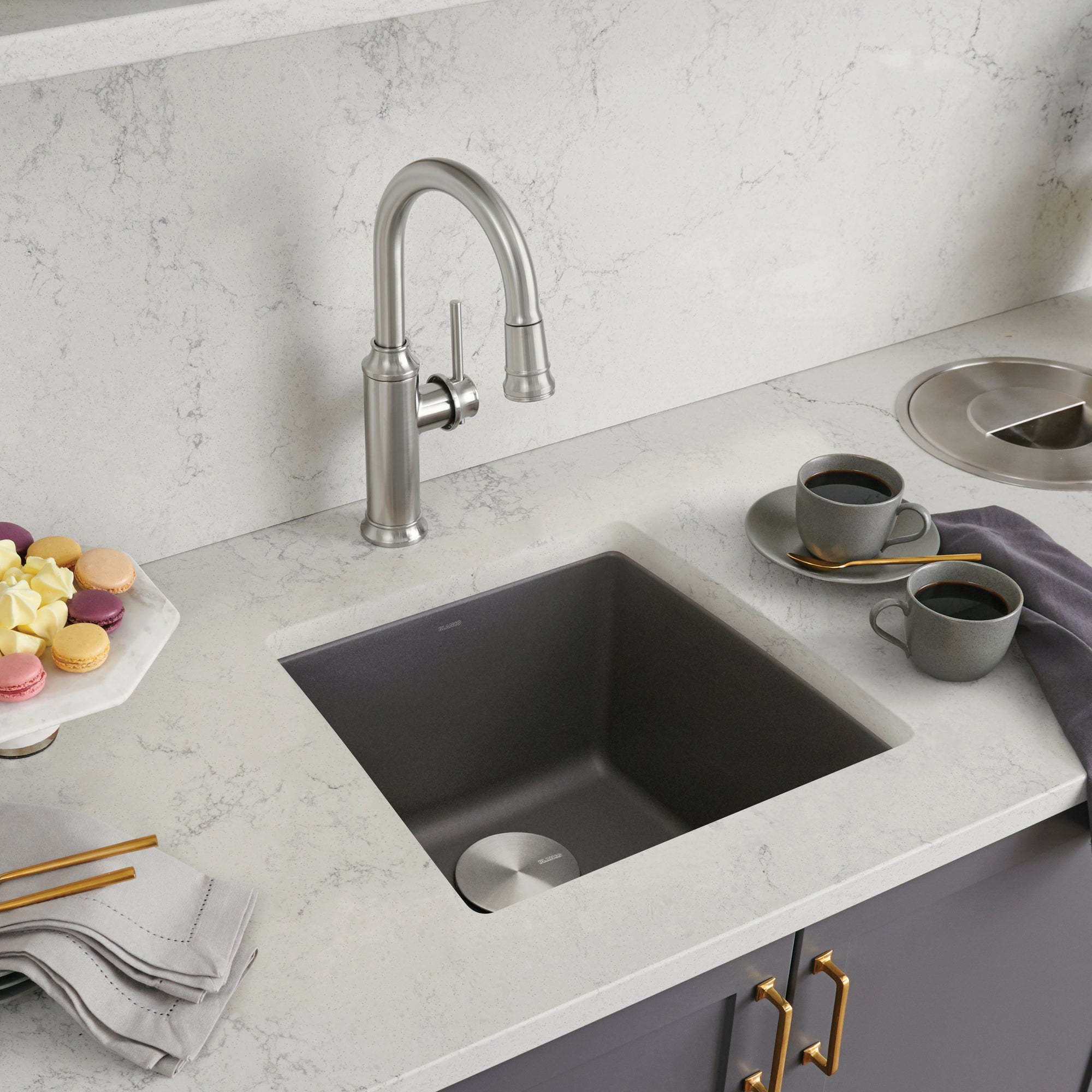 Dark gray square undermount sink with stainless steel faucet installed in white marble countertop.