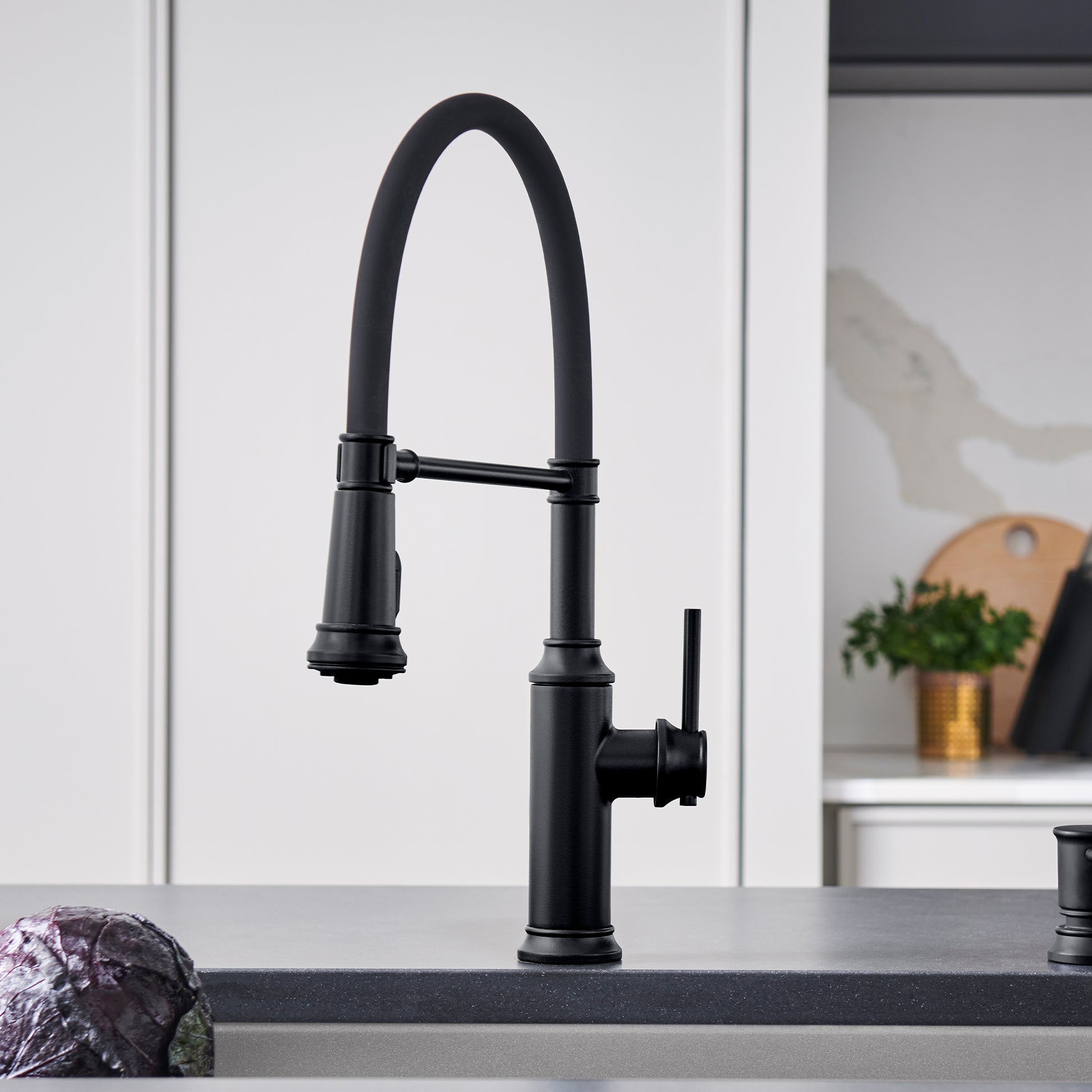 Matte black semi-pro kitchen faucet with tall arched spout and pull-down spray head on countertop.