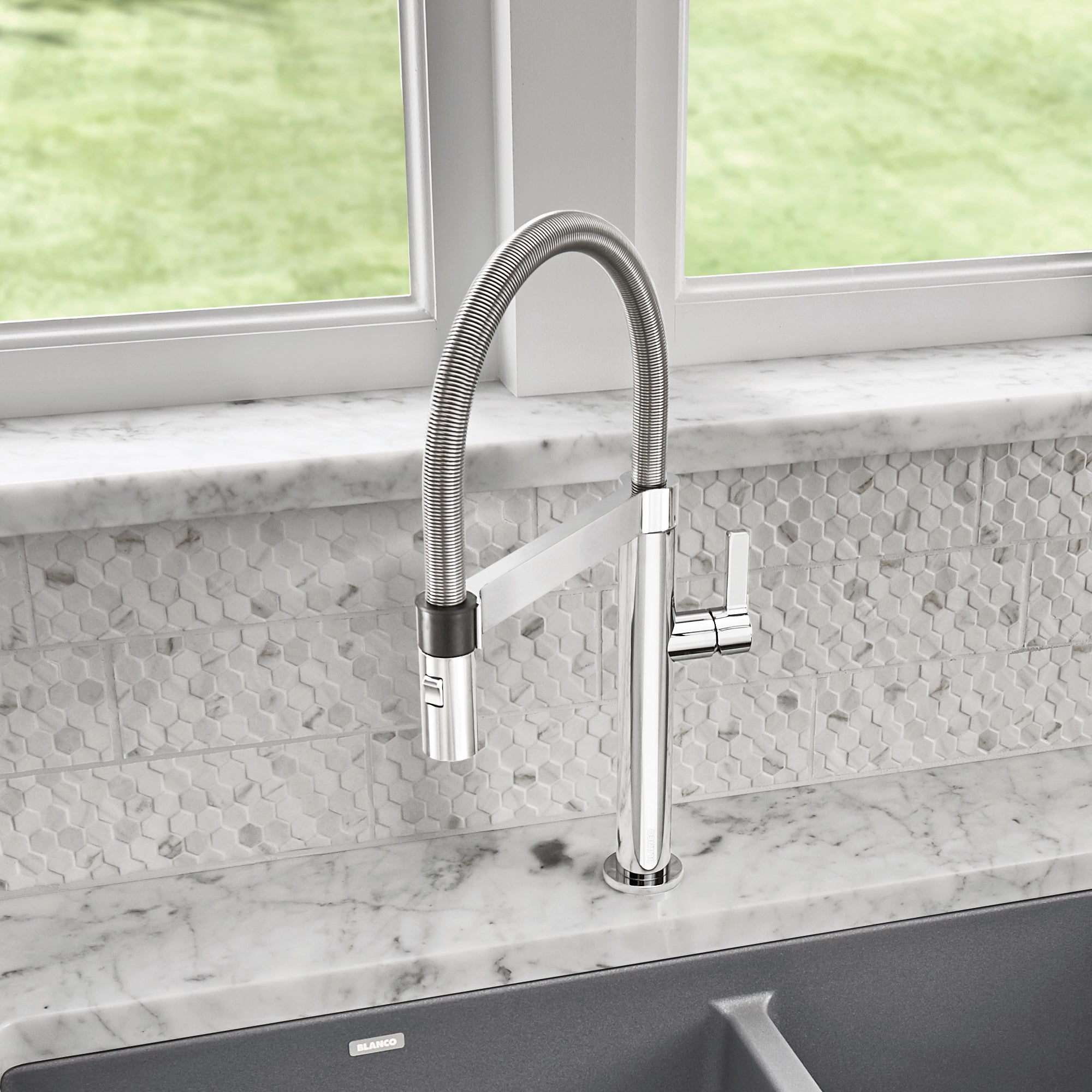 Chrome pull-down kitchen faucet with flexible hose and black grip accent installed above sink.