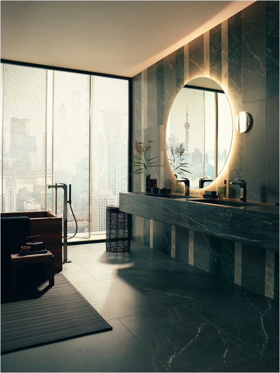 Brushed black chrome freestanding tub filler with handshower mounted beside a freestanding soaking tub in a modern bathroom.
