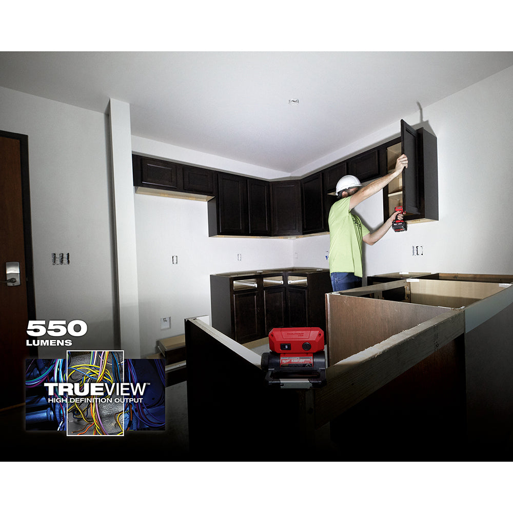 Red and black LED flood light mounted on cabinet, illuminating kitchen work area during renovation.