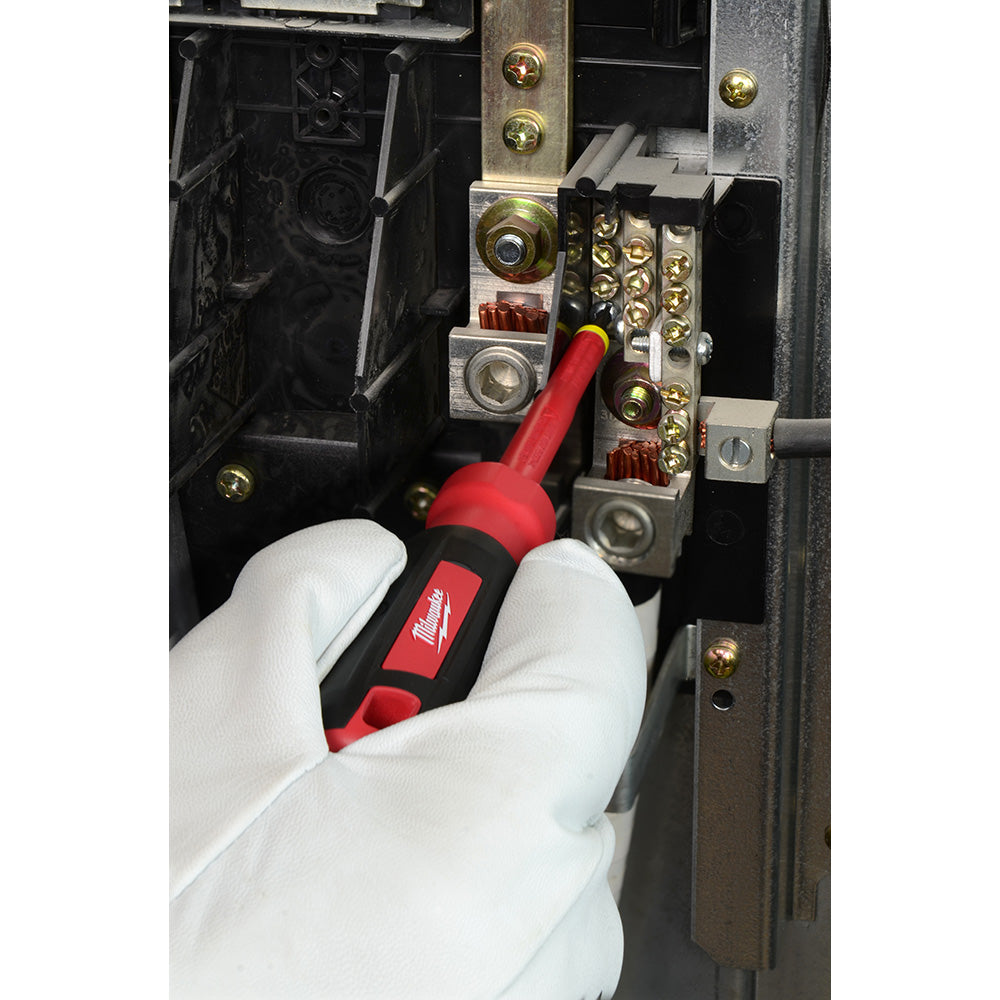Red and black insulated screwdriver with square tip being used on electrical panel with brass terminals.