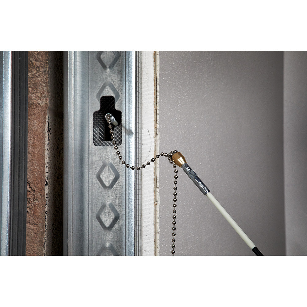 Long white and black rod with magnetic tip attached to metal ball chain, retrieving a screw from a wall stud.