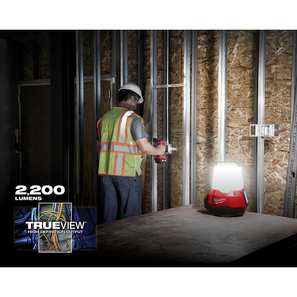 Red and black compact work light with white dome illuminating a construction site interior.