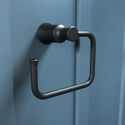 Matte black towel ring with cylindrical mounting bracket and curved rectangular loop mounted on blue wall.