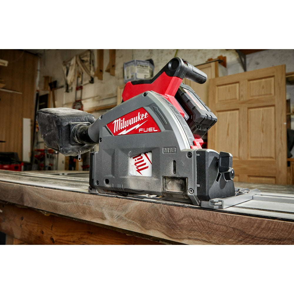 Milwaukee FUEL track saw with red and gray housing mounted on aluminum track cutting into wooden board.