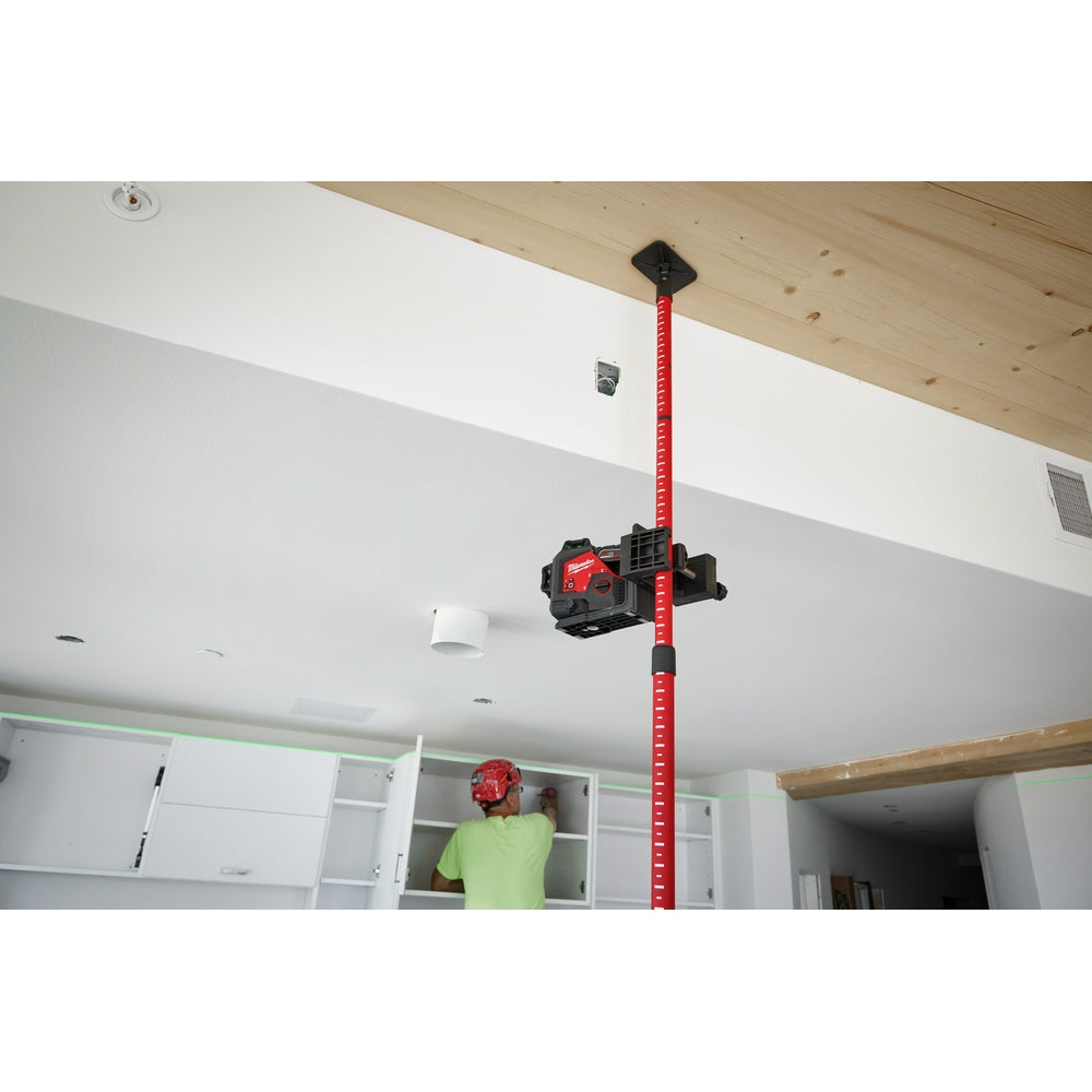 Red and black telescoping laser pole extended toward ceiling with laser level mounted at top.