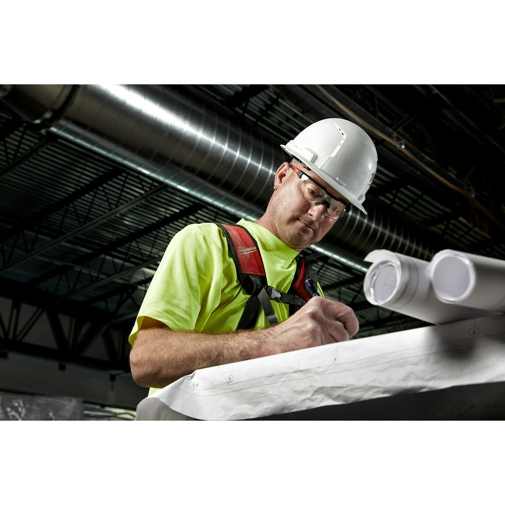 Clear safety glasses with magnified lenses worn by construction worker in hard hat and safety vest.