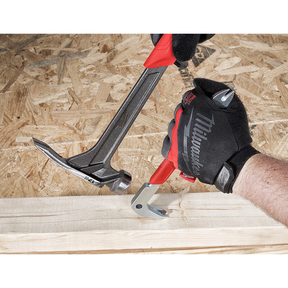 Black and red nail puller with curved claw head being used to extract a nail from light wood surface.