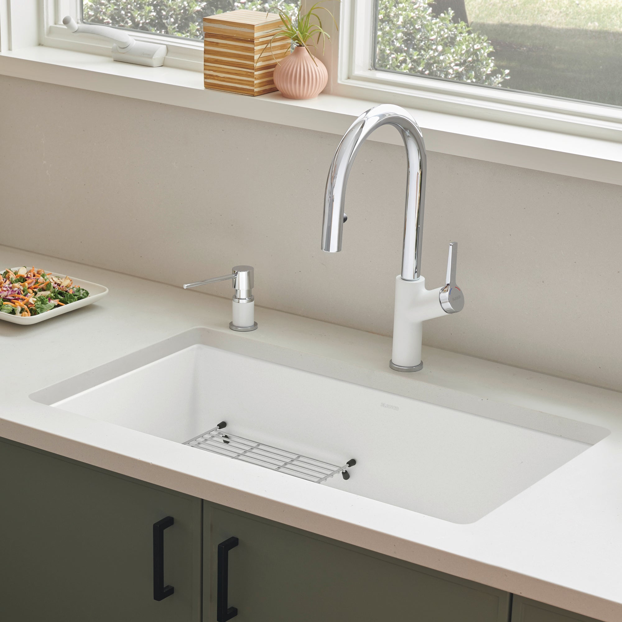 White undermount kitchen sink with chrome pull-down faucet and soap dispenser on countertop.