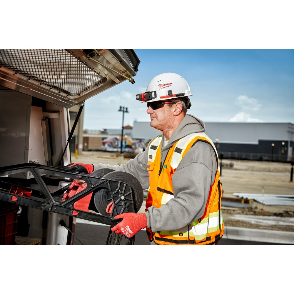 Worker wearing Milwaukee safety glasses with tinted lenses while working on construction site.