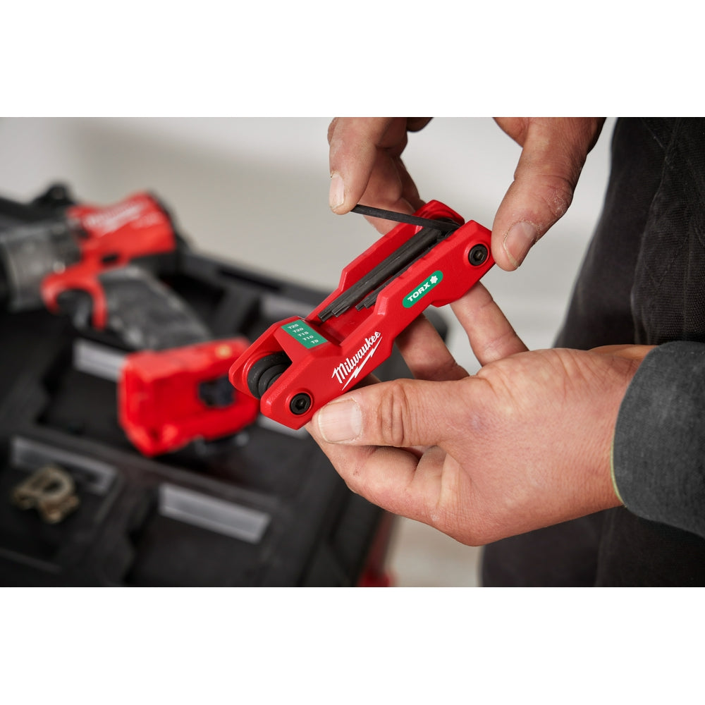 Red Milwaukee folding hex key set with eight Torx keys stored in compact holder, held in hands.