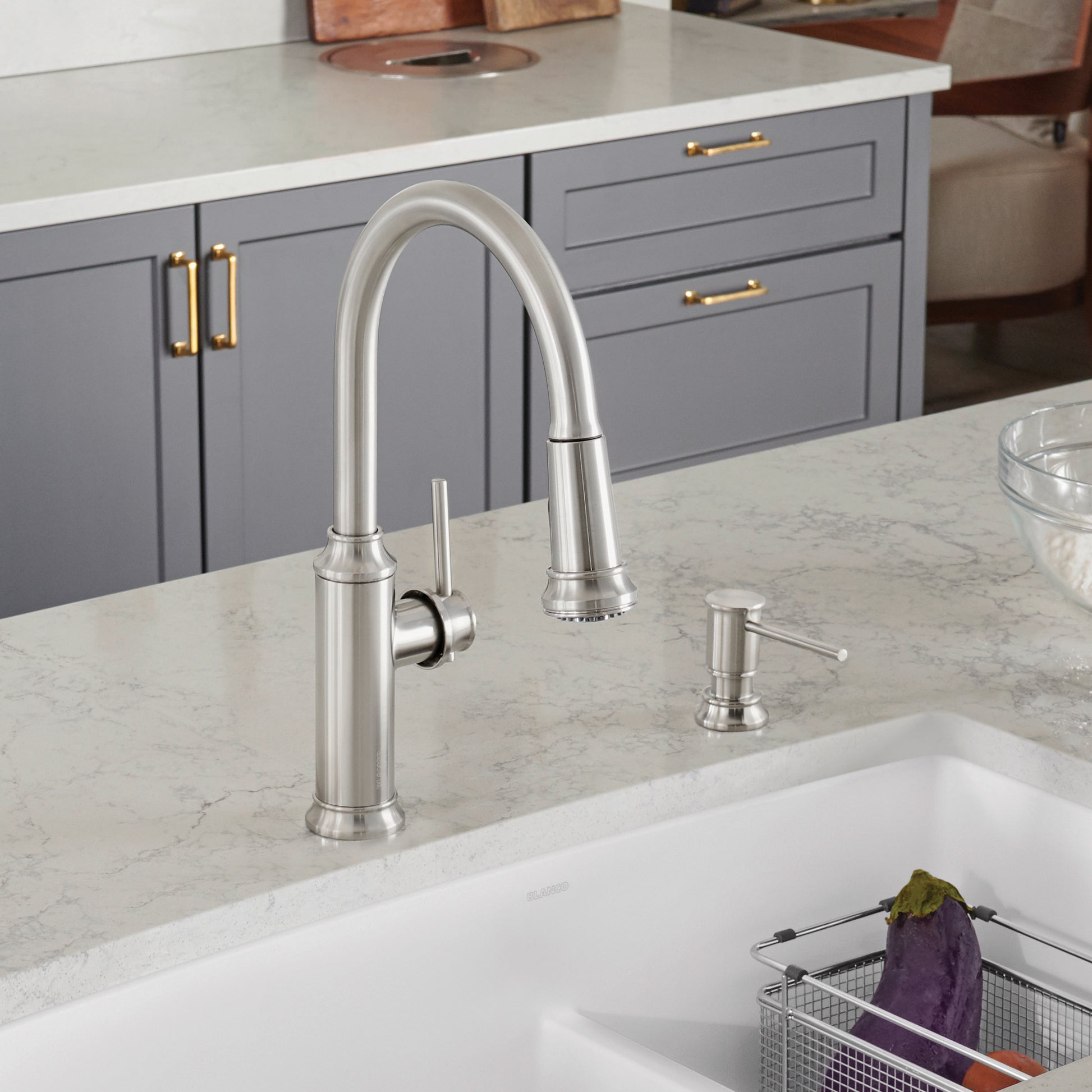 Stainless steel pull-down kitchen faucet with curved spout and lever handle installed above white sink.
