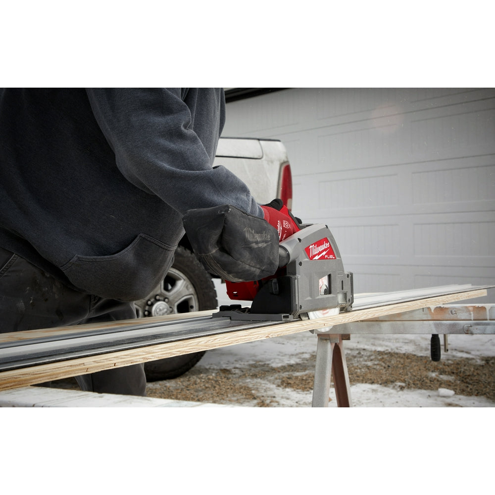 Red and gray Milwaukee guide rail connector mounted on aluminum track with wooden board during use.