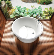 White oval freestanding soaker bathtub with raised seat on wood deck, viewed from above.