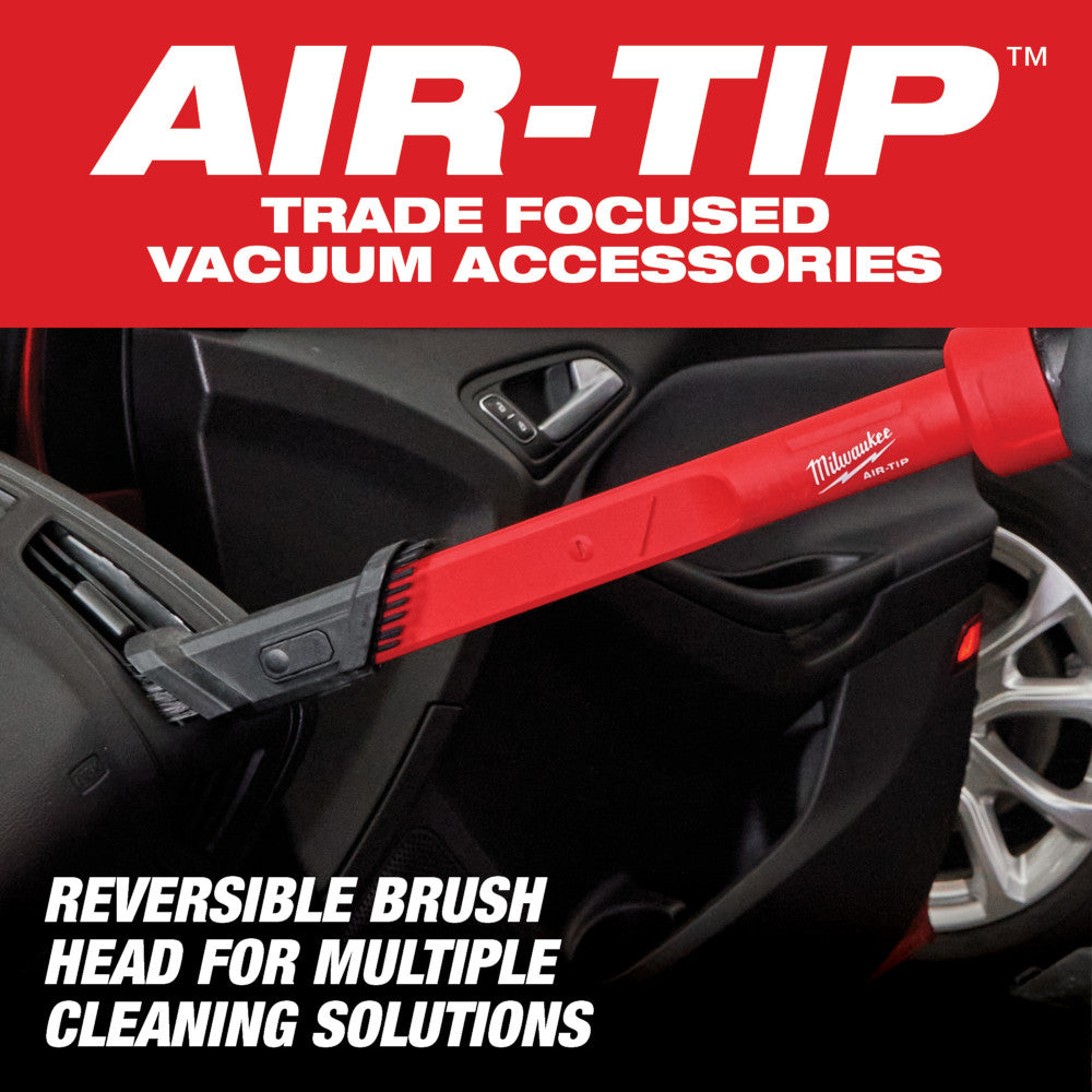 Red and black Milwaukee AIR-TIP vacuum tool with reversible brush head being used to clean vehicle interior door panel.