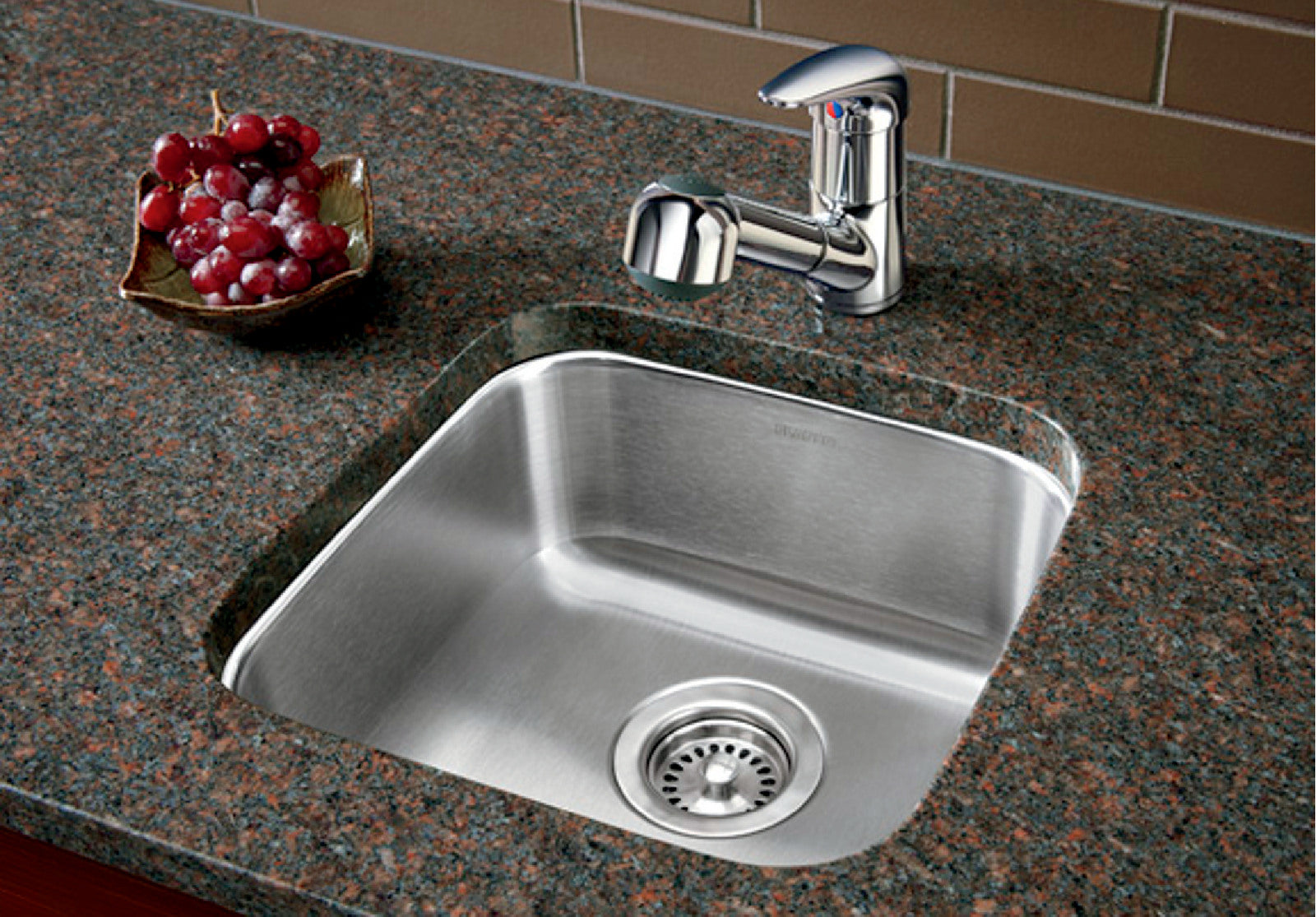 Stainless steel undermount bar sink with chrome faucet installed in granite countertop.