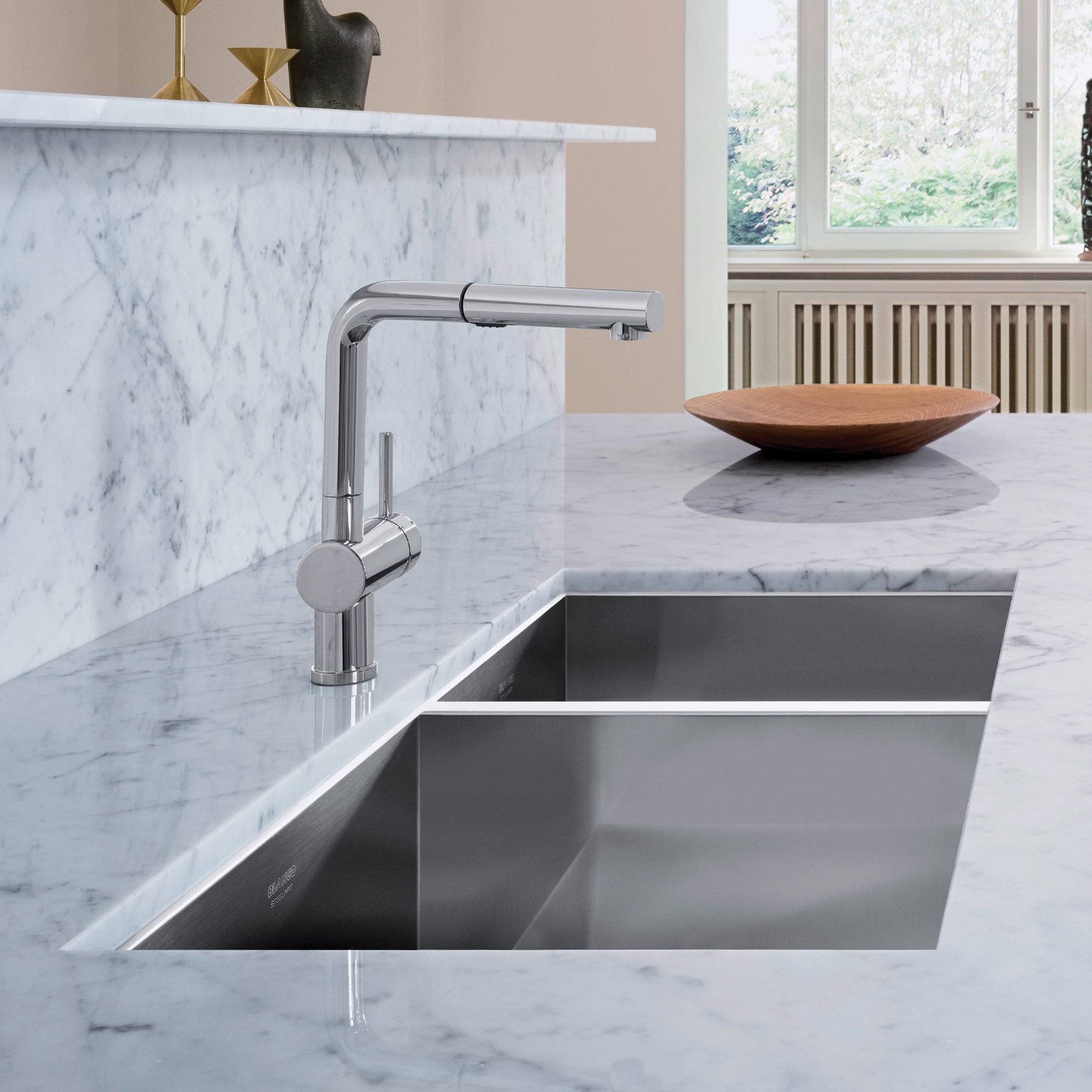 Stainless steel undermount sink with two unequal basins and chrome pullout faucet in marble countertop.