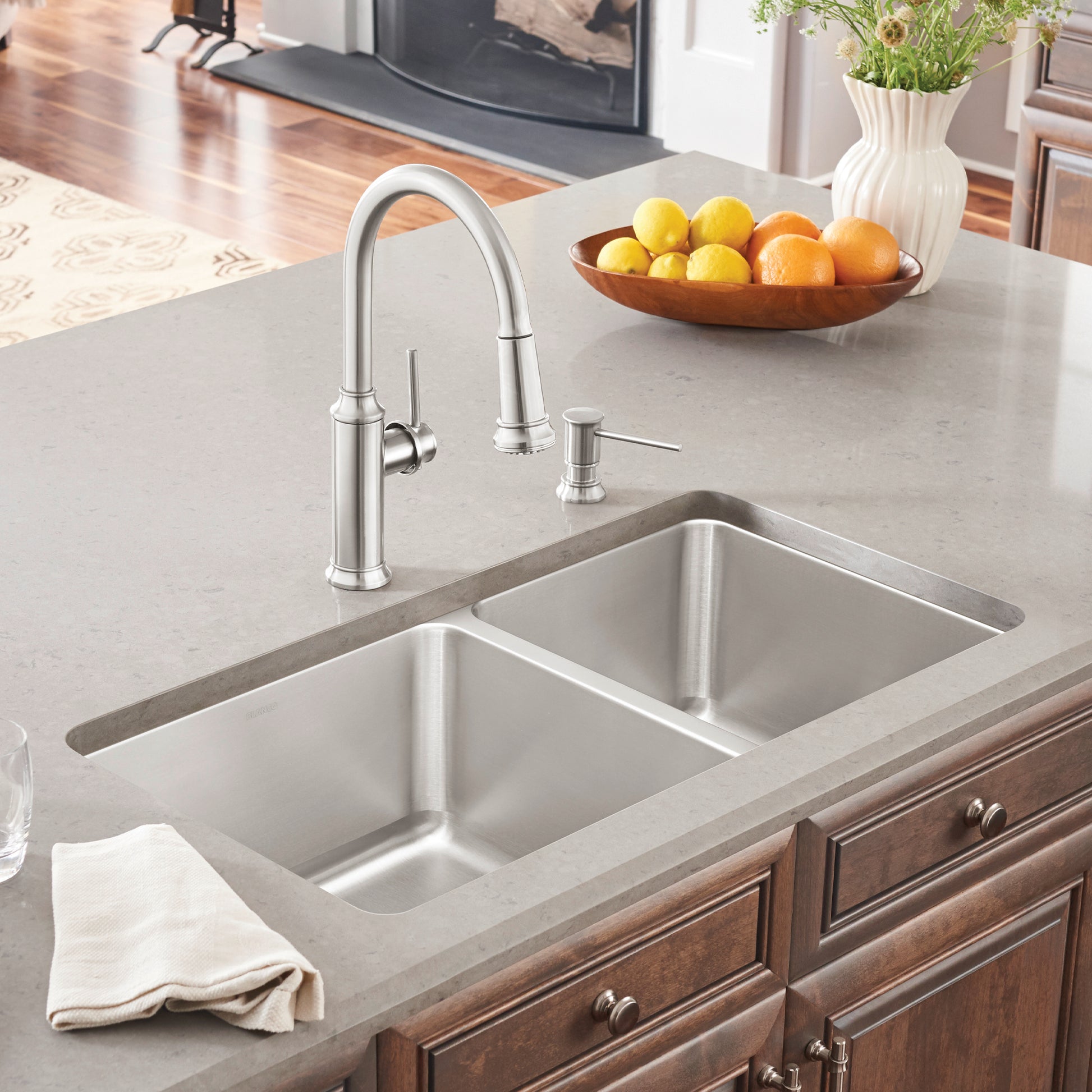 Stainless steel double bowl undermount sink with chrome pull-down faucet and soap dispenser in light gray countertop.