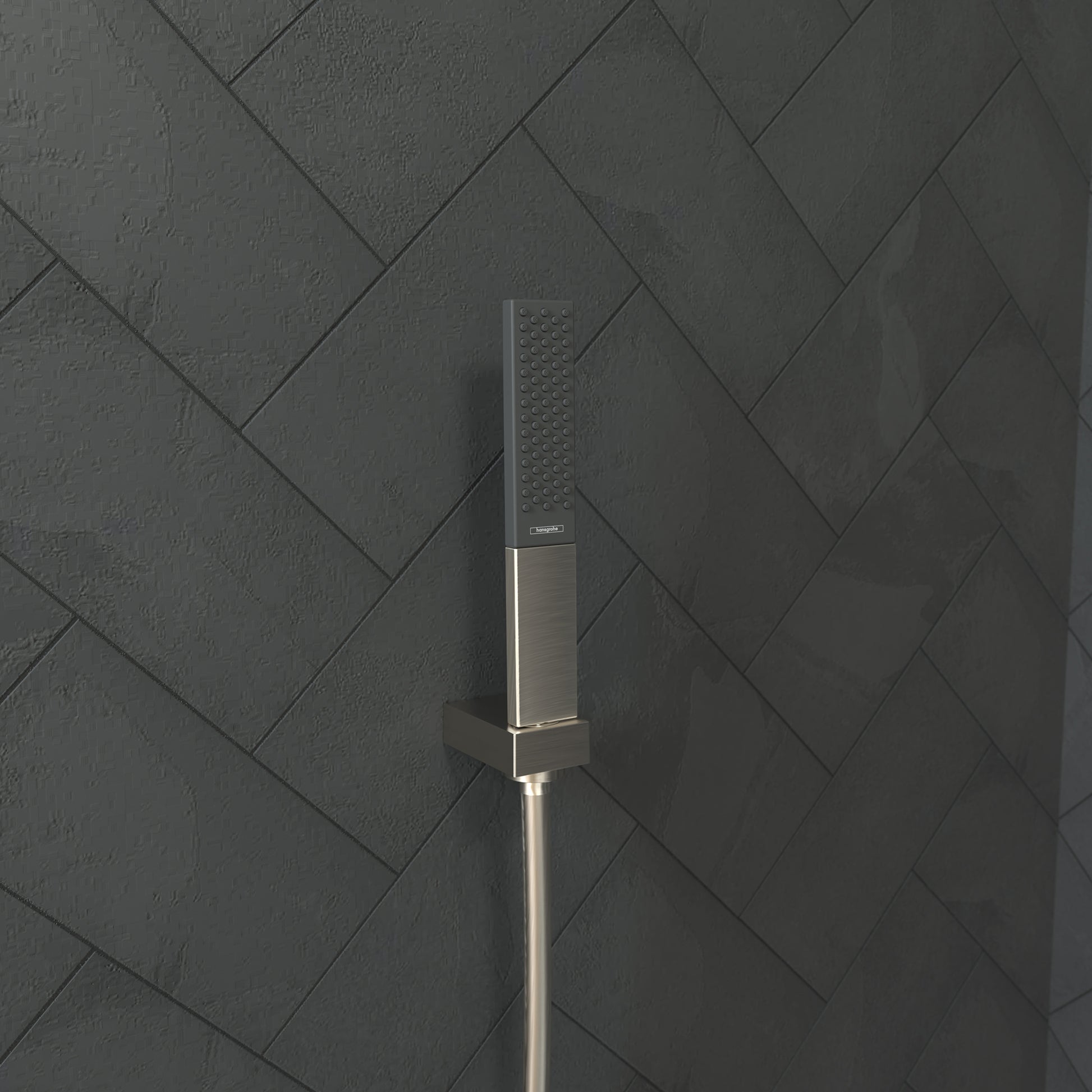 Brushed nickel rectangular handheld showerhead with perforated spray face mounted on a vertical hose against herringbone tile