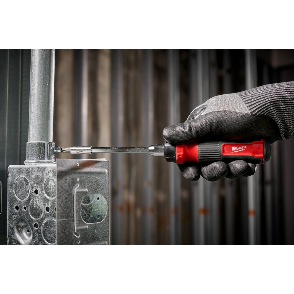 Milwaukee ratcheting screwdriver with red and black handle being used on metal surface.