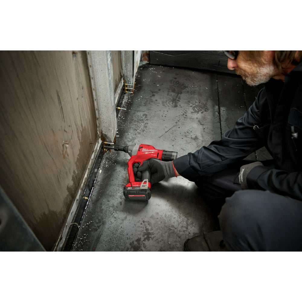Red Milwaukee M18 FUEL rivet tool with battery pack being used by a worker to fasten rivets into metal surface.