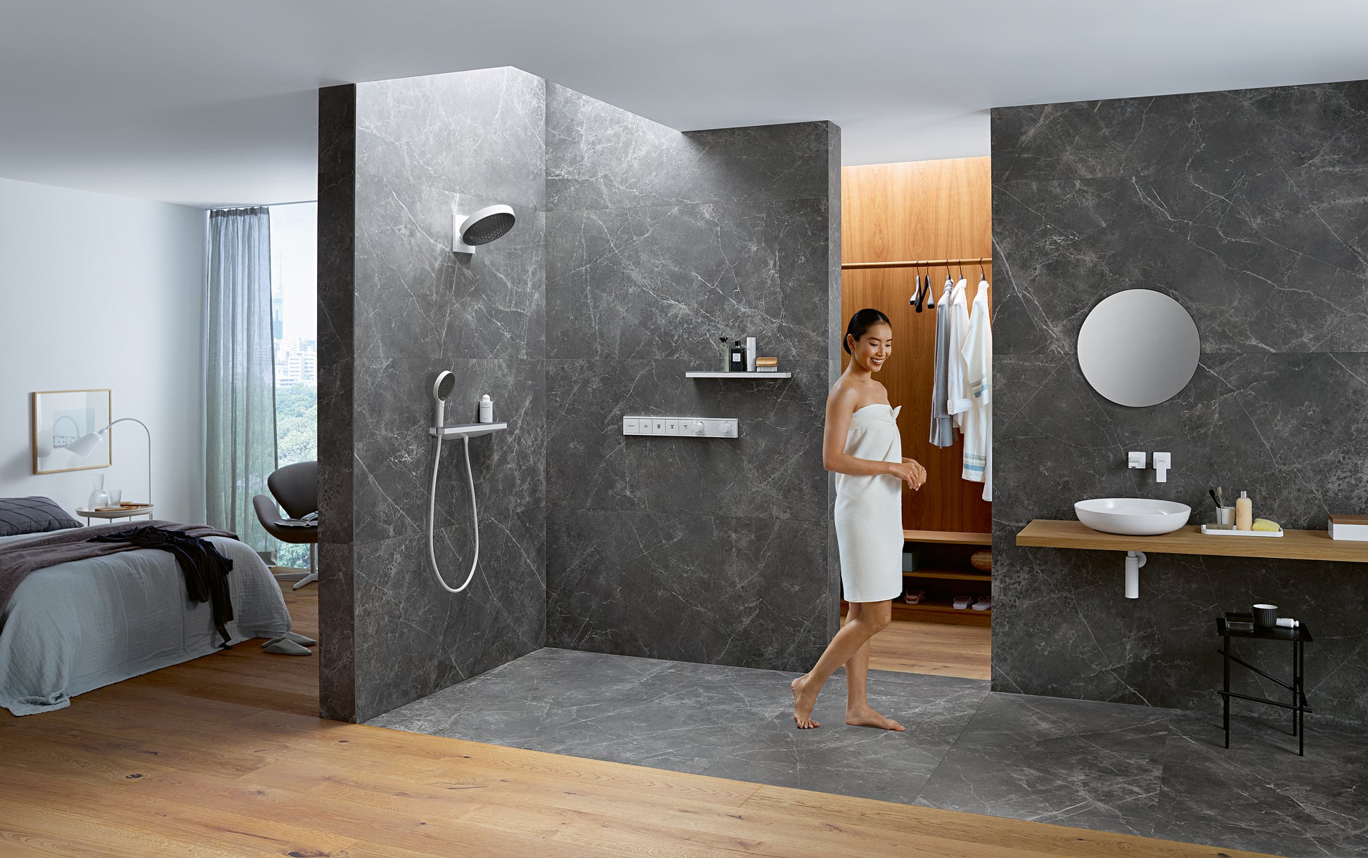 Matte white round shower head mounted on dark tile wall with handheld spray wand below it.