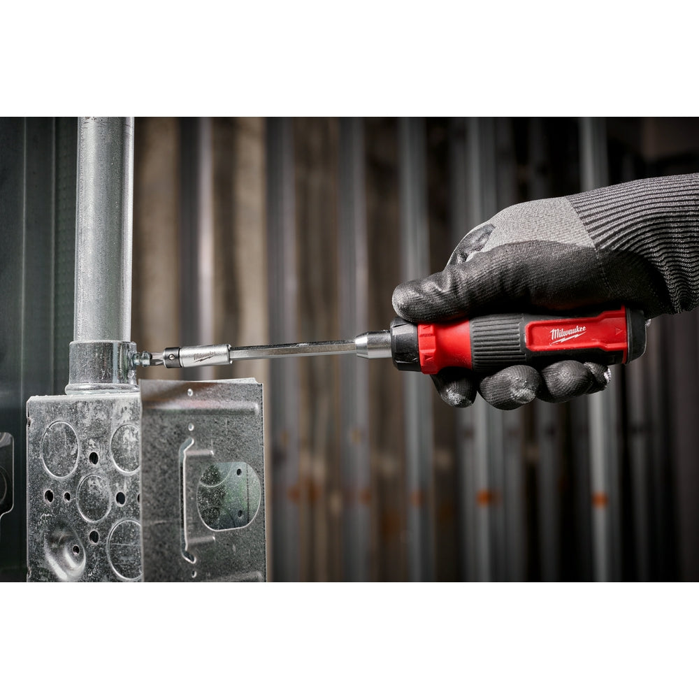 Milwaukee ratcheting multi-bit screwdriver with red and black handle being used on metal surface.