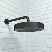 Matte black round rainfall shower head with curved wall-mounted arm against white subway tile.