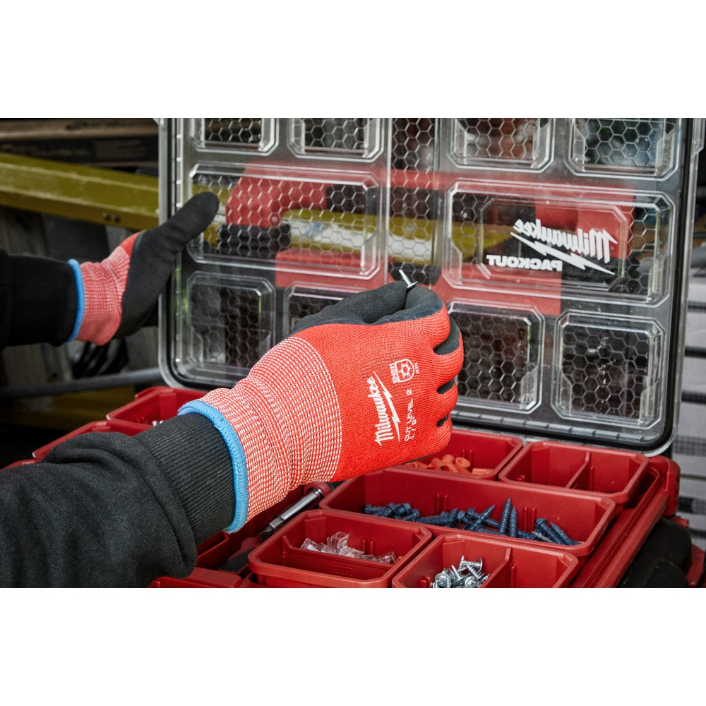 Red and black winter dipped gloves with blue cuff worn over black sleeves near a storage organizer.