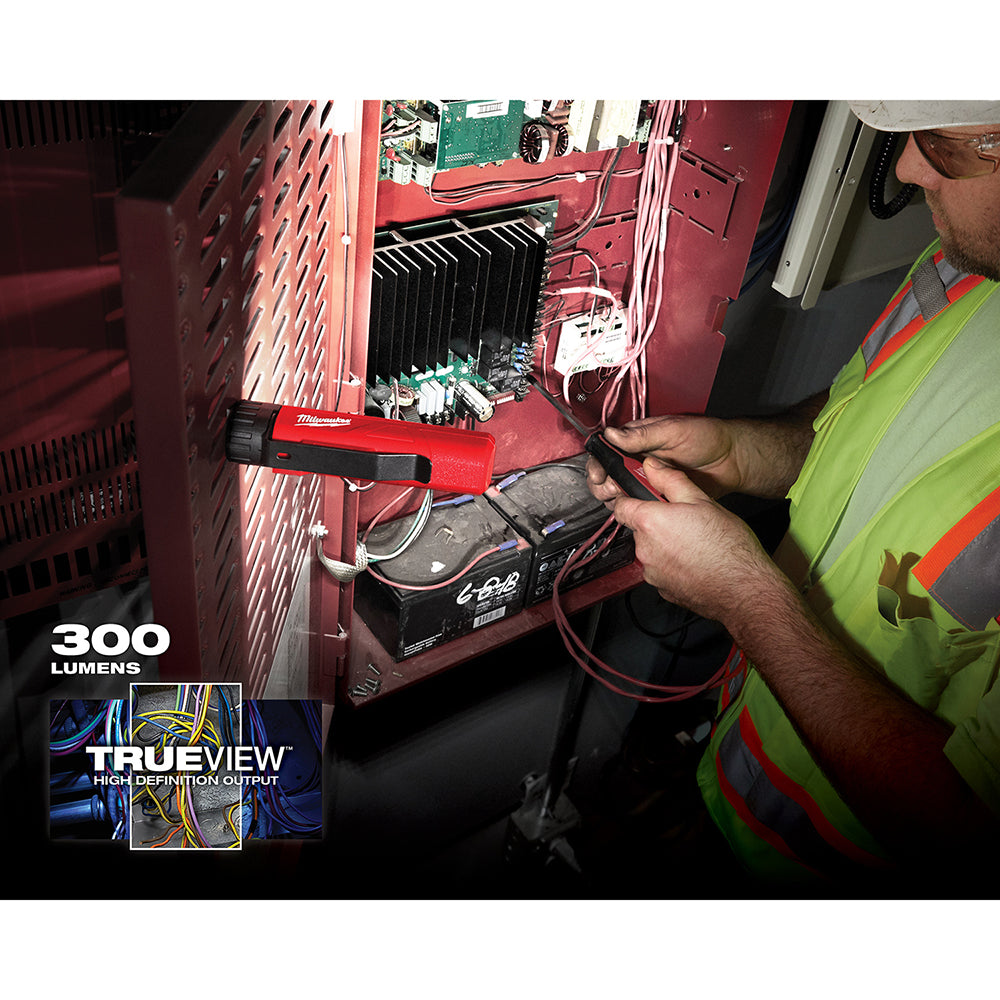 Red and black Milwaukee LED work light with magnetic base being held near electrical equipment, 300 lumens output.